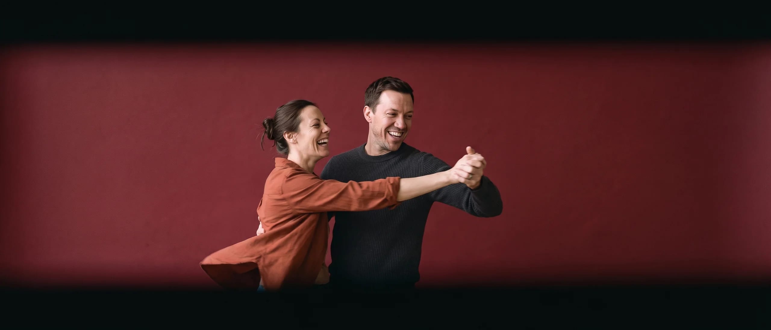 Two people dancing badly and laughing at it, her shirt flared with the turn
