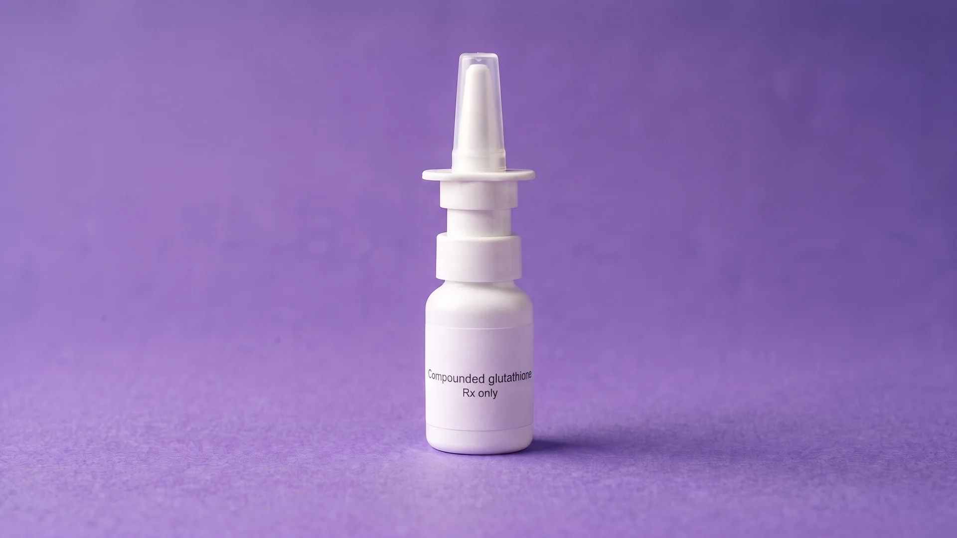A plain white nasal spray bottle labelled Compounded glutathione, Rx only, standing on iris paper