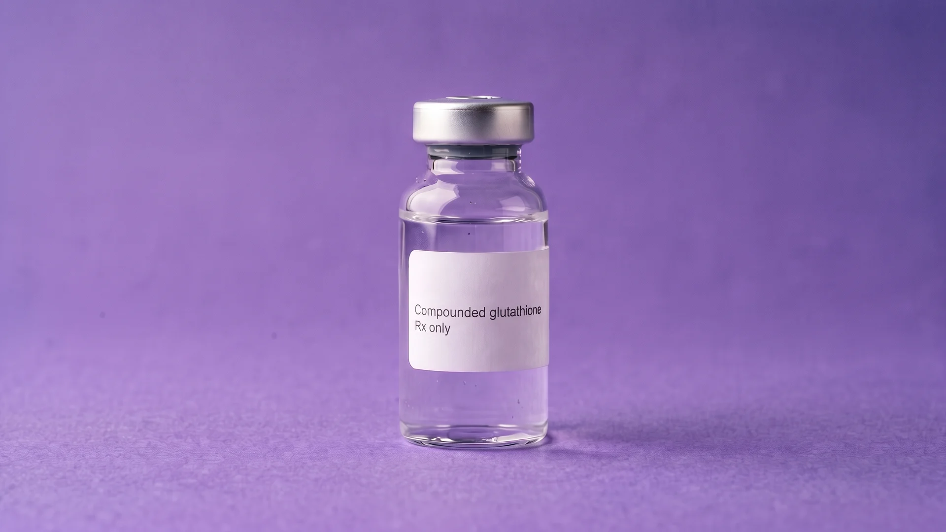 A clear glass vial labelled Compounded glutathione, Rx only, standing on iris paper