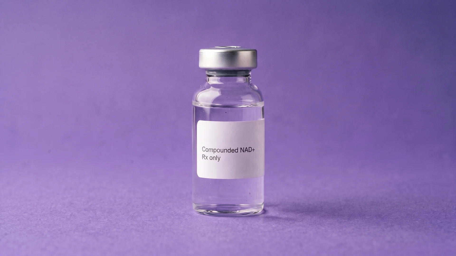 A clear glass vial labelled Compounded NAD+, Rx only, standing on iris paper