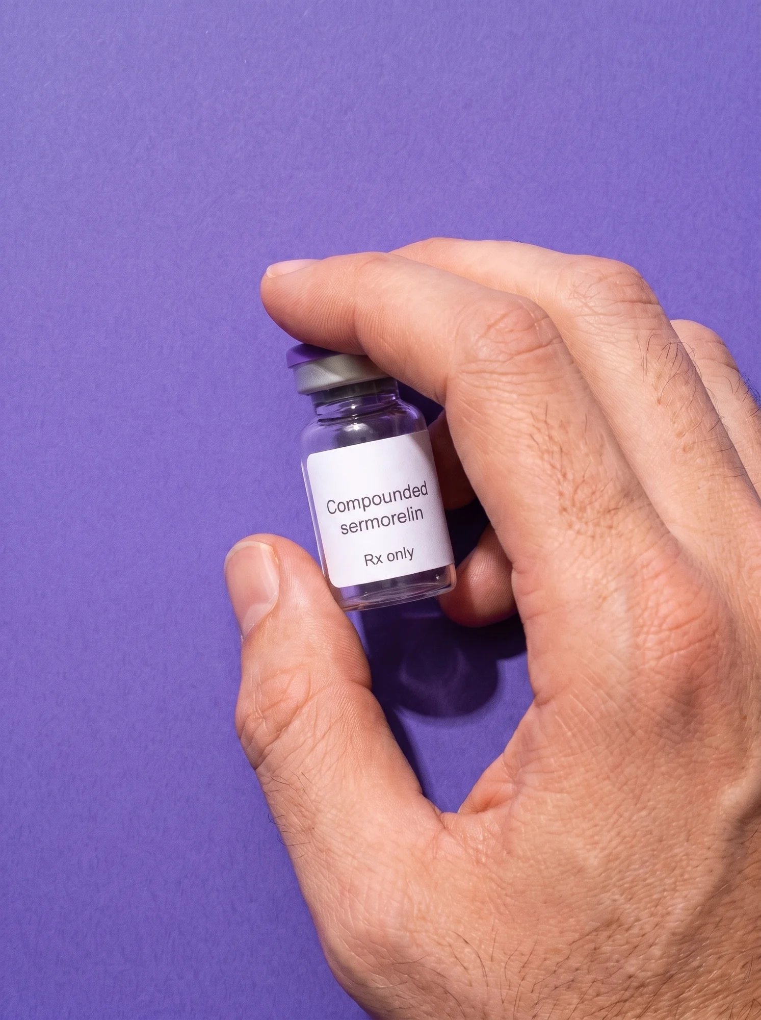 A hand setting down a vial labelled Compounded sermorelin, Rx only, fingers running off the frame