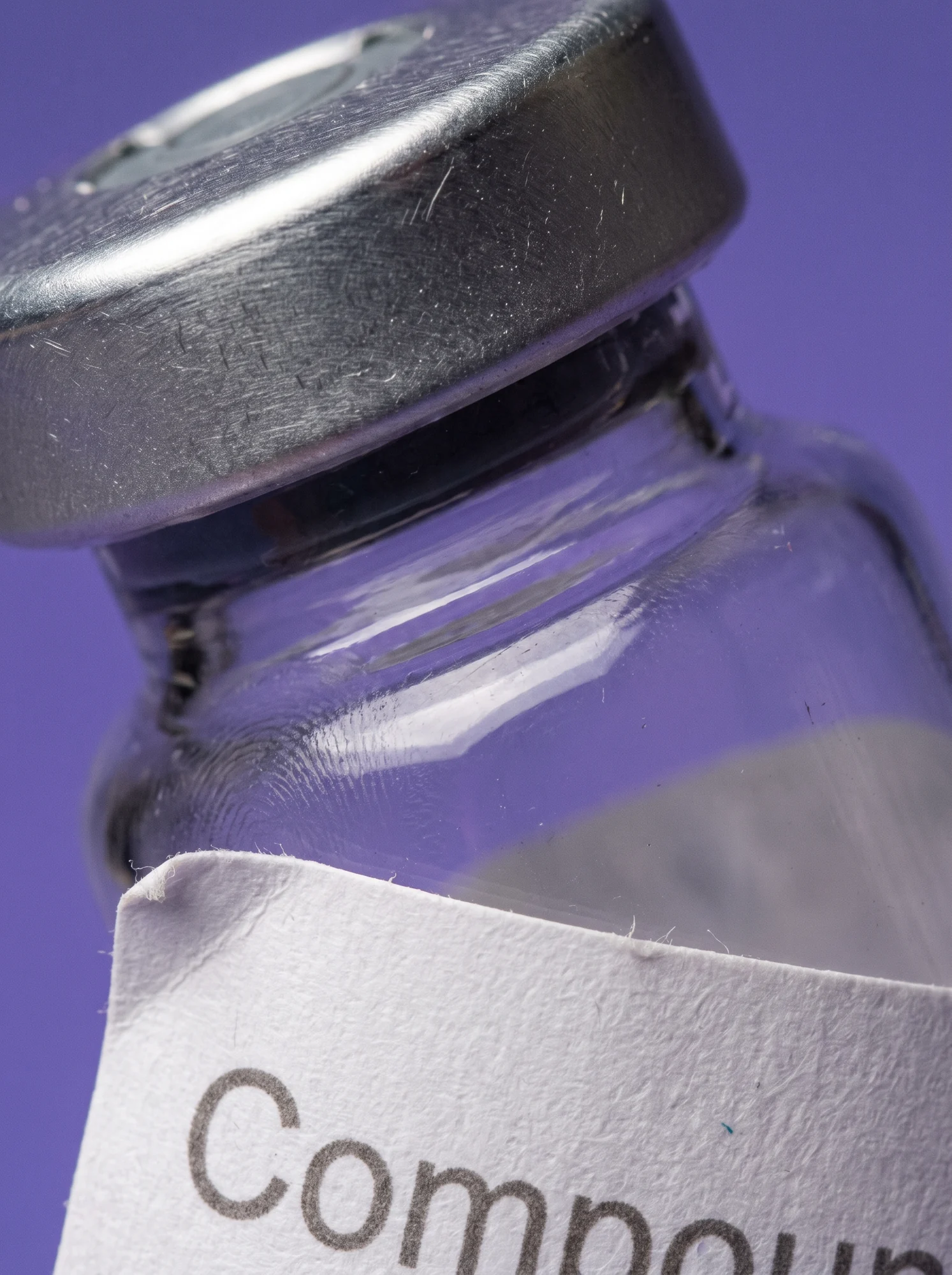 Macro of the flip-off cap and the edge of the plain white label on a clear vial