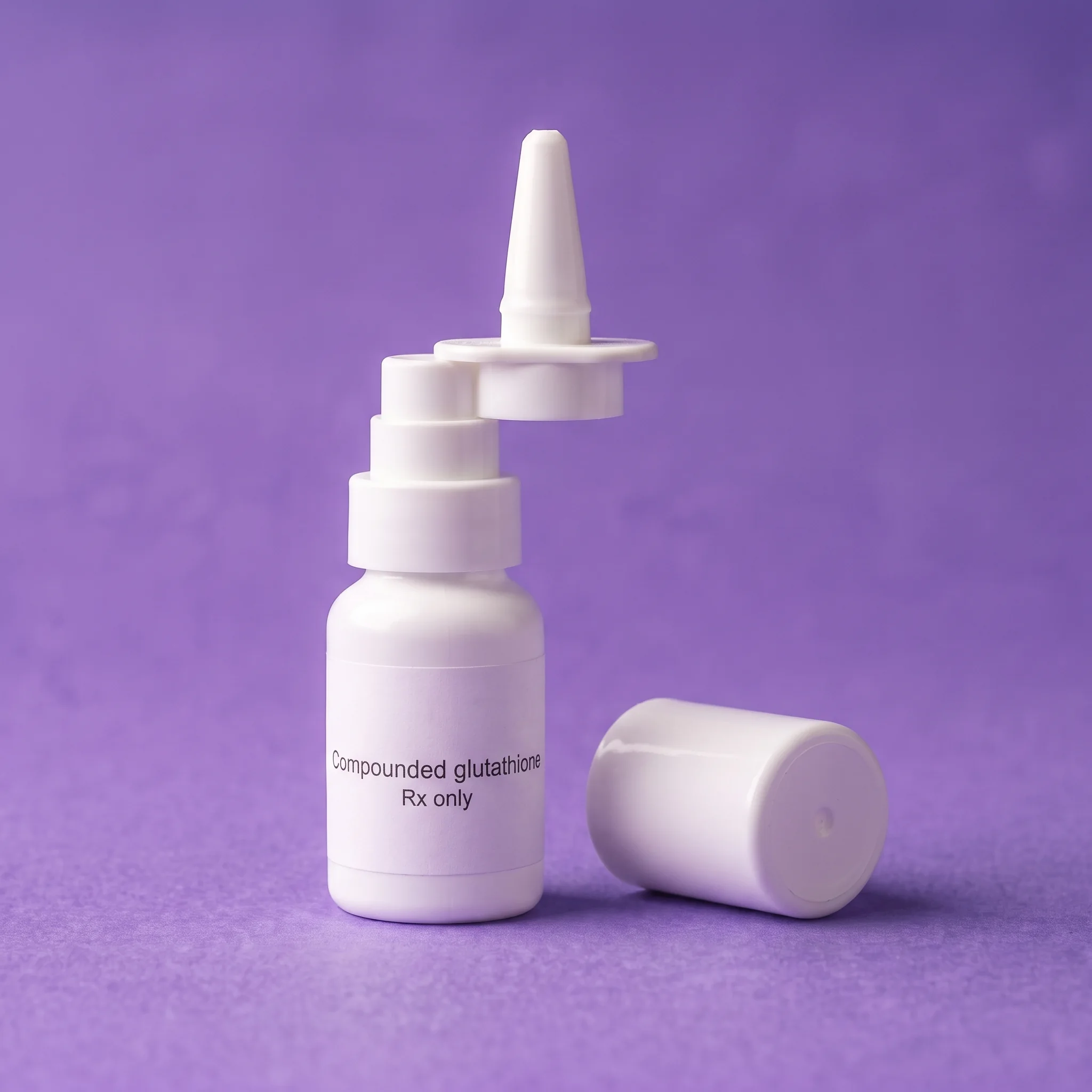 The sprayer bottle with its cap off beside the cap on iris paper