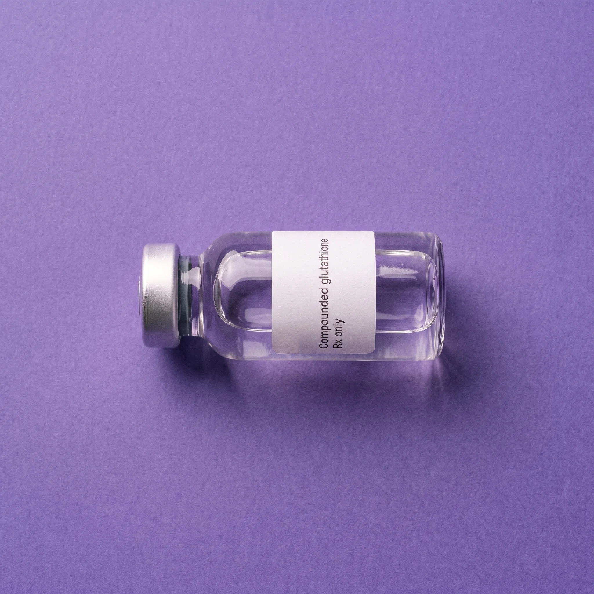 The Compounded glutathione vial laid on its side on iris paper