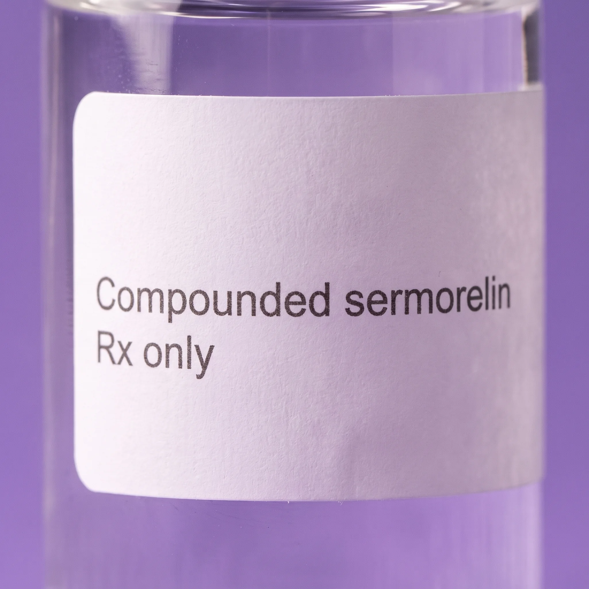 Macro detail of the plain white label, reading Compounded sermorelin above Rx only