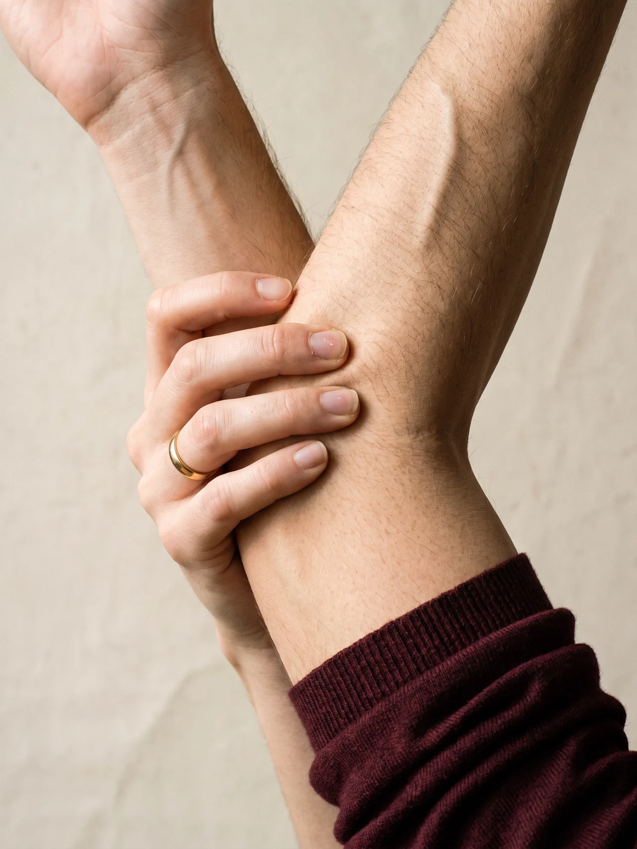 A hand closed around a forearm, cropped at wrist and elbow, no faces