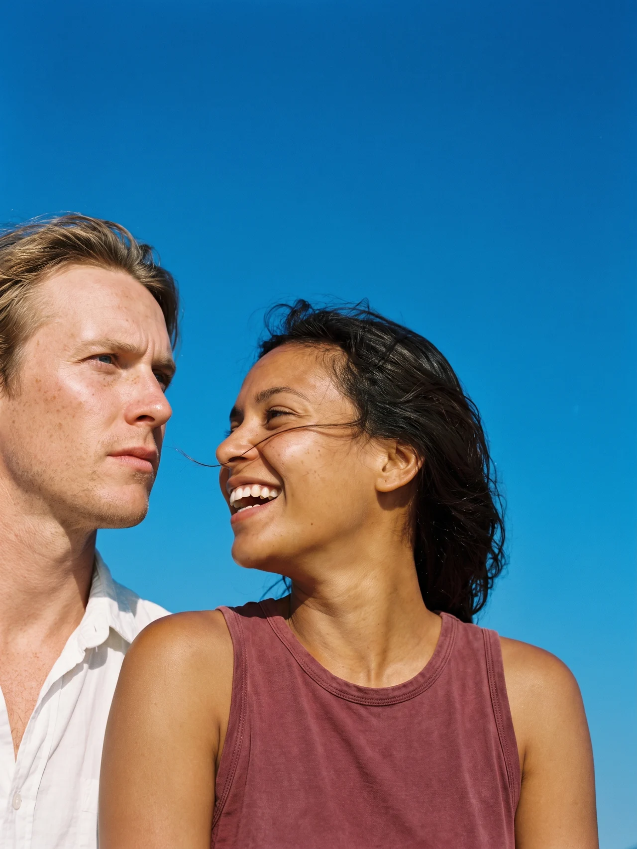 Two people in profile against open sky, one laughing