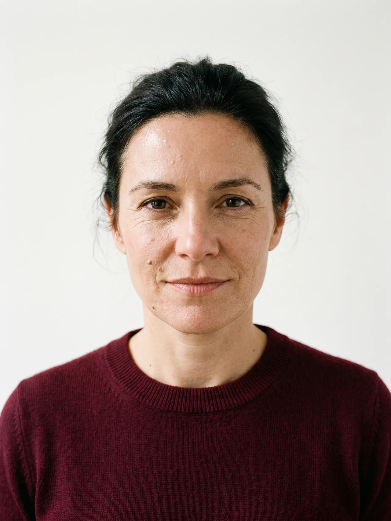A woman in her forties looking straight into the lens, bone seamless paper behind