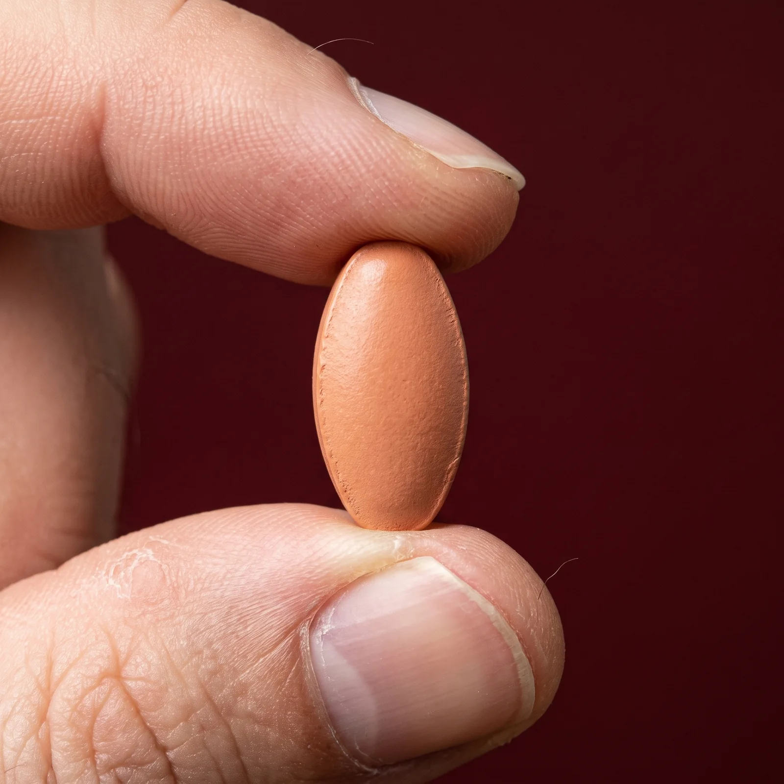 Macro of a single tablet held between a fingertip and thumb