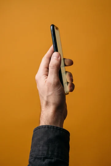 A hand holding a phone against amber seamless